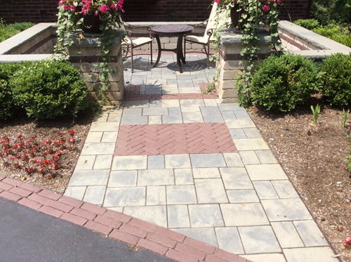 backyard unilock paber patio with reds, browns and blacks and pillars with lights