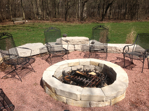 GRAVEL SURROUNDING FIRE PIT WITH LARGE BOULDERS USED FOR THE SEAT WALL