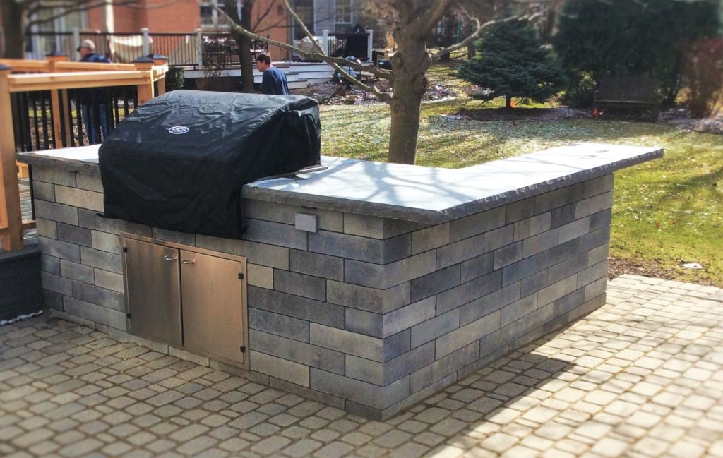 OUTDOOR KITCHEN WITH GRILL BUILT INTO UNILOCK PAVER PATIOS