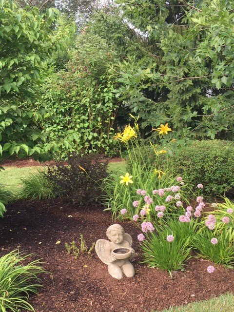 baby angel statue with yellow and purple flowers within garden design